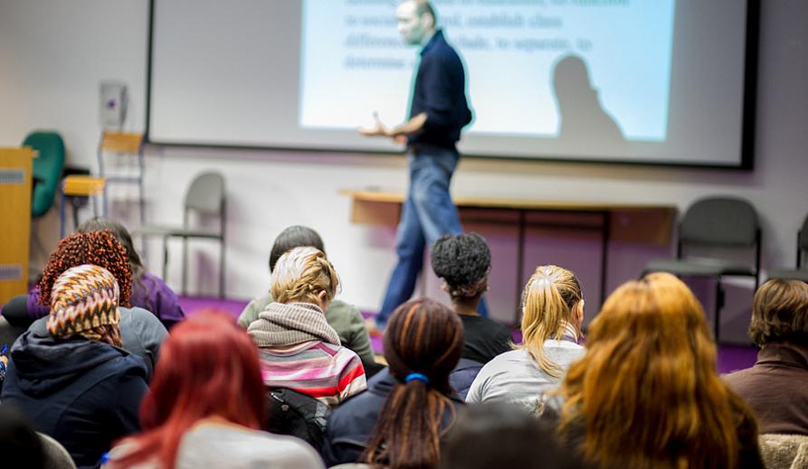 A lecturer delivering presentation in the classroom full of students