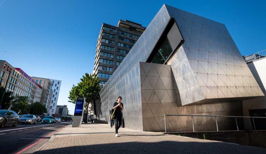 A person walking past the London Met Graduate Centre and Tower Building.