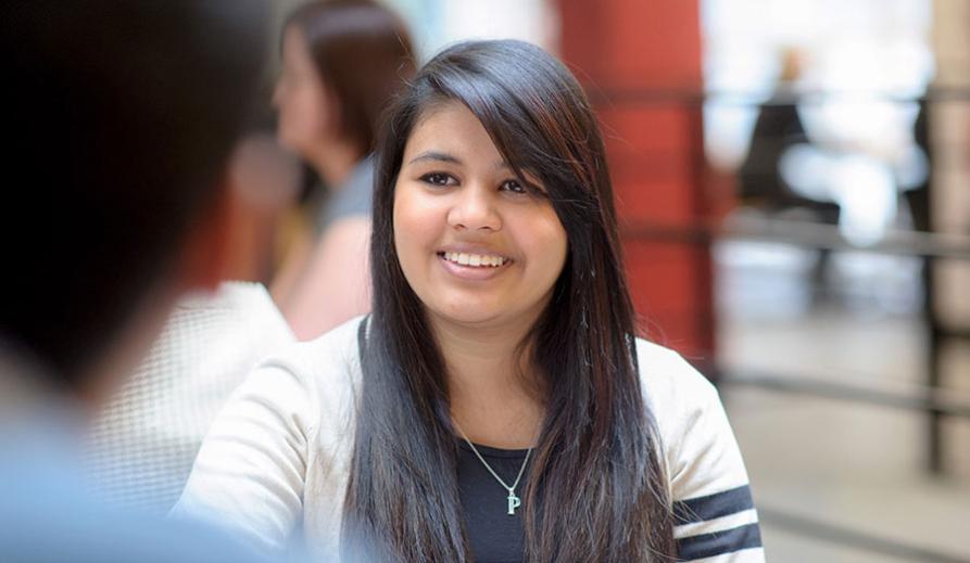 Woman smiling while facing another person who is out of shot. 