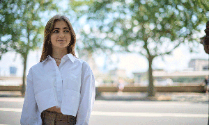 A girl standing outside with trees in the background